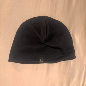 Svart mössa från Haglöfs - En stilren svart mössa från Haglöfs i mjukt och stretchigt syntetmaterial. Perfekt passform och enkel design med liten logotyp framtill. Sitter skönt på huvudet och funkar lika bra till vardags som till träning utomhus.