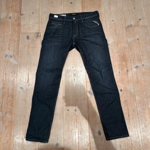 Replay Anbass mörkblå jeans - Snygga mörkblå Replay Anbass jeans med klassisk femficksdesign och kontrastsömmar. Jeansen har en slim passform och är tillverkade i ett stretchigt jeansmaterial som sitter skönt. Perfekta för dig som gillar stilrena och moderna jeans.