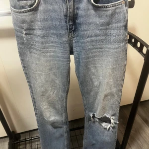 Blå straight jeans från g perfect jeans (pris kan diskuteras)  - Säljer ett par blå jeans från g perfect jeans i rak modell. Jeansen har slitningar och ett stort hål på ena knät för en cool, avslappnad look. Klassisk femficksdesign och normal passform. Perfekta för dig som gillar en streetig vibe.