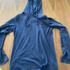 Blå hoodie från Polo Ralph Lauren - Säljer en snygg blå hoodie från Polo Ralph Lauren. Tröjan är i helt ok skick. Storlek XS.