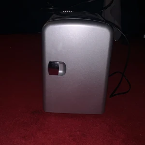 Mini kylskåp med värme- och kylfunktion - Kompakt mini kylskåp i silver med både värme- och kylfunktion. Kan drivas med både 12V DC och 220V AC, perfekt för bil eller hem. Utrustad med ventilationsgaller och reglage för temperatur. Skick: bra, mindre yttre slitage syns.
