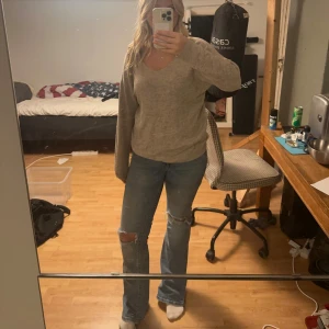 Beige stickad v-ringad tröja - Mysig beige stickad tröja med v-ringning och långa ärmar. Tröjan har en avslappnad passform och är perfekt för lager-på-lager. Enkel och stilren design som funkar till det mesta.