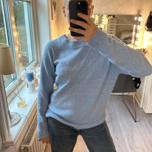 Ljusblå stickad tröja med rund hals ifrån Vero Moda - Mysig ljusblå stickad tröja med rund halsringning och ribbade muddar. Tröjan har en enkel och clean look, perfekt att slänga på sig över ett par jeans. Långärmad och i mjukt material som känns skönt mot huden. Använd kanske 3 gånger 🩵