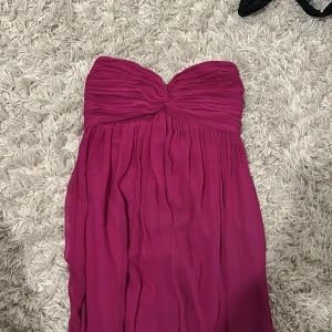 Balklänning  - Säljer min superfina axelbandslösa rosa/lila balklänning. Klänningens färg är mest lik första bilden, den är inte lika neon som den ser ut på sista. Den har bara använts ett fåtal gånger så i superbra skick! 