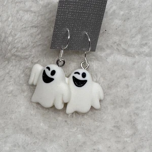 Spökörhängen i vitt och svart - Roliga örhängen med vita spöken som har svarta detaljer för ögon och mun. Perfekta för dig som vill sticka ut med ett lekfullt och unikt smycke. Hängande modell med metallkrok i sterling silver.