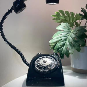 Retro svart bordstelefon med nummerskiva - Klassisk svart bordstelefon med roterande nummerskiva. Telefonen har en unik retrodesign och är i gott skick med mindre repor och slitage. 