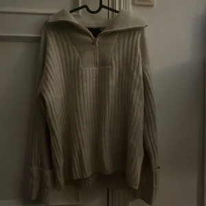 Beige ribbstickad half zip från Pieces - Ribbstickad beige tröja från Pieces med halv dragkedja och hög krage. Oversized fit med långa ärmar och breda muddar. 