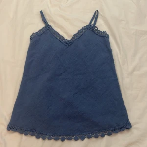 Blå spetstopp - Snygg blå camisole med V-ringning och fin spets vid halsen och nederkanten. Använd typ bara några få gånger. Köpt på en marknad i Slovenien❣️❣️ 