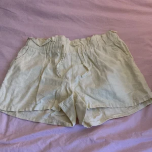 Beige linneshorts med snörning Lindex 💛✨✨✨ - Säljer ett par ljusbeige shorts från Lindex i mjukt linne. De har elastisk kant och snörning framtill, samt fickor på sidorna. Perfekt för varma dagar och chill stil. Passar dig som gillar relaxed vibe och naturliga material. 💛💛💛
