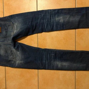 Exklusiva Jeans West – Japansk denimkvalitet - säljer ett par riktigt snygga och unika jeans från jeans west established 1977. de här jeansen är tillverkade med fokus på kvalitet och hantverk, med klassisk selvedge denim och fina detaljer som grön och röd kantstickning på insidan. märket står för autentisk jeanskultur, inspirerad av klassiskt västerländskt arbete och japansk precision.