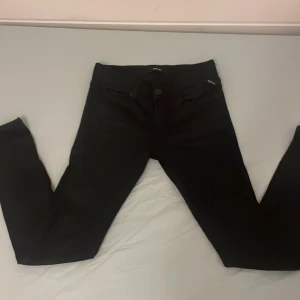 Svarta Replay jeans  W27 L30 - Säljer ett par svarta Replay LUZ jeans i storlek W27 L30. Byxorna har klassisk femficksdesign, smal passform och snygga Replay-detaljer på fickorna. Materialet är stretchigt och bekvämt. Väldigt bra pris, tveka inte efter frågor.