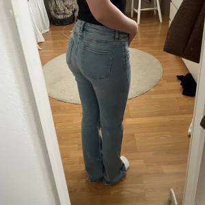 Bootcut jeans från Gina Tricot ljusblå - Snygga ljusblå bootcut jeans från Gina Tricot Young i storlek 164. Passar en 34/XS Modellen har låg midja, klassiska fem fickor och rå kant nedtill för en chill vibe. Jeansen är tillverkade i mjukt denim och passar perfekt till sneakers eller boots.