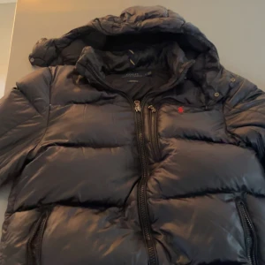 Svart pufferjacka från Polo Ralph Lauren - Sjukt snygg svart vinter jacka från Polo Ralph Lauren i bra skick. Köptes förra året här på plick och har behandlats bra. Nypris på en sån här jacka ligger på cirka 6000 kr. Vårt pris är 2999! Priset kan diskuteras vid snabb affär!
