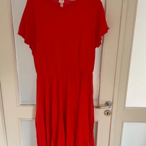 Röd långklänning från H&M L.O.G.G. - Snygg röd långklänning från H&M L.O.G.G. i storlek XL. Klänningen har rund halsringning, korta ärmar och ett lätt rynkat midjeparti som ger en chill siluett. Tillverkad i mjuk bomull som känns skön mot huden. Perfekt för dig som gillar färgstarka looks.