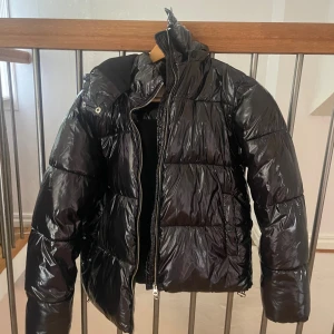 Svart pufferjacka från Nelly - Säljer en vinterjacka  från Nelly i modellen: shine puffer jacket. I storlek S. Köpt förra vintern och inte så mycket använd, ända defekten är jackhängaren som har gått av. Perfekt för kalla dagar när du vill hålla stilen och värmen.