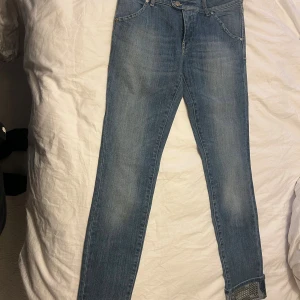 Blå skinny jeans från MET med nitar - Snygga blå jeans från MET i modellen twenty 27 seven. Jeansen har skinny passform och är tillverkade i stretchig denim. Fållarna är uppvikta och dekorerade med coola nitar för en extra edge. Klassiska fickor både fram och bak samt dubbla knappar i midjan.