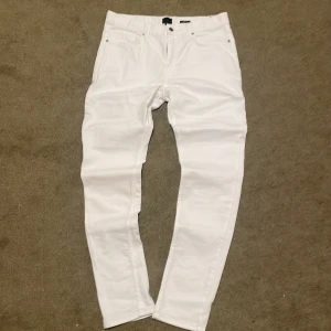 Vita slim fit jeans i storlek 32 - Säljer ett par vita slim fit  jeans i storlek 32. Byxorna har klassisk femficksdesign och smal passform hela vägen ner. Perfekta för dig som gillar stilren look. Materialet är mjukt och stretchigt för extra komfort.