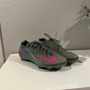 Nike Mercurial blå/rosa fotbollsskor - Säljer mina Nike Mercurial Vapor 16 Elite FG. Använd sparsamt, bara lite svart pågrund av att jag spelar på konstgräs men inget fel på dom.  Köptes för 3299. Pris just nu 2549 kr på unisport. Säljer för 1000 (pris kan diskuteras vid snabb affär)  Perfekta för fotboll på gräs och även konstgräs även fast de är gräs.  Skostorlek: 43