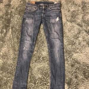 Dondup jeans - Snygga blå jeans från dondup med skinny passform och slitna detaljer på låren och vid fickorna. Klassisk femficksmodell med orange sömmar och dragkedja. Jeansen har en något ljusare tvätt och är tillverkade i jeansmaterial. Jeansen sitter mer som 30/30 än 31. Har en lagning mellan bilden men inget som syns vid användning (Bild 4)