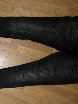 Svart jeans Jack n Jones slim Glenn  - Snygga svarta slim jeans med tvättade detaljer och klassisk femficksdesign. Jeansen har smal passform och är tillverkade i stretchigt denim för en bekväm känsla. Perfekta till en avslappnad streetstyle-look. Jeansen är från Jack n Jones och köpta för 899kr. Skick: 7/10 använt flertal gånger och pytteliten slitning vid Gylfen men absolut redo för en ny användare.