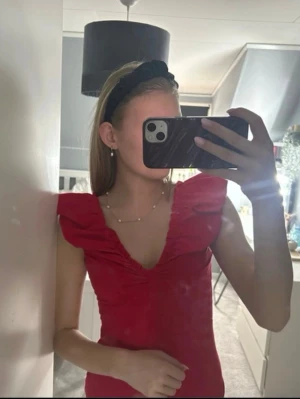 Röd topp med volangärmar - Snygg röd topp med djup v-ringning och volangdetaljer vid axlarna. Toppen är figurnära och har öppen rygg, vilket ger en trendig look. Perfekt att styla med jeans eller kjol för en cool outfit. Nu utan prislapp 