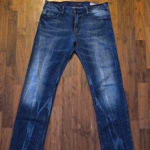 Blå Armani Jeans J45 Regular Fit - W33 L32 - Snygga blå jeans från Armani Jeans, modell J45 Regular Fit. Klassisk femficksdesign med AJ-läderpatch och logga på bakfickan. Jeansen har en rak passform och coola slitningar för en modern look. Perfekta för dig som gillar stilrena och trendiga jeans.