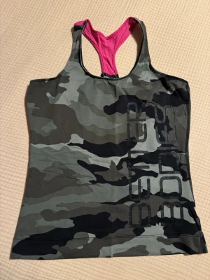 Träningslinne från Better Bodies - Kamouflagemönstrat träningslinne med rosa detalj från Better Bodies. Storlek S. Brottarrygg. Använt fåtal gånger, fint skick.