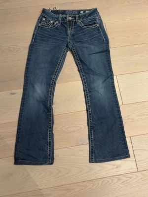 Mörkblå Miss Me bootcut jeans - Snygga mörkblåa miss me jeans i storlek 26. De har skosnören inuti jeansen för att knyta pågrund av att de är lösa vid midjan, men det går att ta bort om det önskas.  