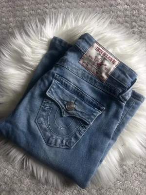 True Religion ljusblå jeans - Säljer ett par ljusblå jeans från True Religion storlek 24, dom är som nya! Använd fåtal gånger då jag fått nya. Inga skador, de är bara o buda