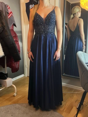 Balklänning  - Säljer min Mörkblå balklänning med smala axelband och v-ringning både fram och bak. Jag är 158cm och har sytt upp klänningen hos en skräddare. Den har en slits på ena sidan. När jag har på mig den utan skor är den 3 cm från marken. Skulle säga att den passar någon som är lika lång som mig eller kortare beroende på vilka skor man har till! Den är i storlek 32💕 Minns inte vart den är ifrån men är ganska säker att jag köpte den på jj house eller bubbleroom! Köpt för lite mer än 3000kr
