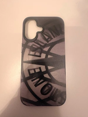 Svart mobilskal med Stone Island-tryck - Snygg stone Island mobilskall för iPhone 16! Den är så bra genom att skydda mobilen jag har sålt min telefon och behöver inte den. Jag har haft den typ 1 månad aldrig tappat mobilen med den så den är helt ny ungefär.         