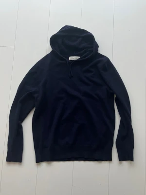 Kashmir hoodie - En stilren mörkblå hoodie med huva och dragsko. Tillverkad i ett mjukt och bekvämt material, perfekt för en avslappnad look. Hoodien har långa ärmar och en klassisk passform utan tryck eller mönster. Fint skick från sayless! Storlek M men sitter mer som S