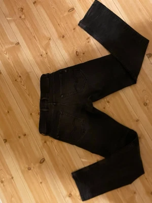Replay svarta slim fit jeans - Säljer ett par svarta Replay jeans med slim passform. Klassisk femficksmodell med svarta sömmar och diskret Replay-logga i linningen. Jeansen är i stretchigt jeansmaterial och har en smal siluett som sitter bra hela vägen ner.