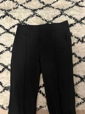 Svarta kostymbyxor med pressveck🖤🖤 - Stilrena svarta kostymbyxor med klassiskt snitt och pressveck framtill. Byxorna har hällor för bälte och sidofickor, perfekta för en dressad look. Passar dig som vill ha en enkel och tidlös stil.