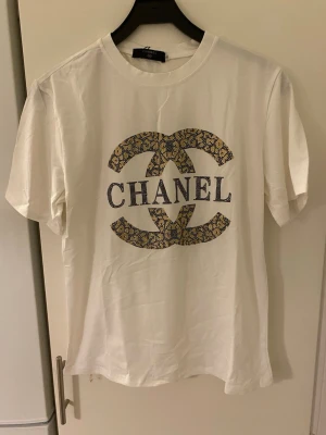 Vit T-shirt med tryck på - Vit t-shirt med tryck på. Är små stenar på trycket över hela trycket.