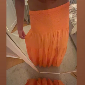 Orange långkjol från Cosy House - Säljer en snygg orange långkjol från Cosy House med volanger. Kjolen är luftig och färgen är riktigt cool. Storlek s