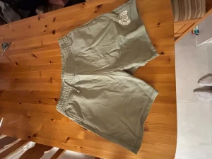 Gröna shorts från Weekday med tryck - Säljer ett par ljusgröna shorts från Weekday i mjuk bomull. De har elastisk midja med snörning och ett vitt Santa Cruz-tryck på ena benet. Perfekta för chill dagar eller träning.