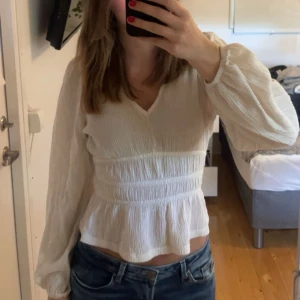 Vit blus med v-ringning och volang - Säljer en söt vit blus med v-ringning från Lindex i stl XS, använd fåtal gånger!