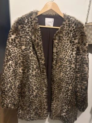 Leopardmönstrad pälsjacka från Mango - Säljer en fluffig och trendig leopardmönstrad pälsjacka från Mango. Jackan har lång ärm, öppen front och är fodrad med brunt tyg. Perfekt statement-plagg för dig som vill sticka ut och hålla dig varm.