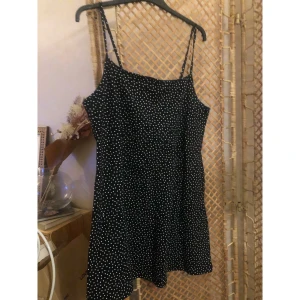 Svart prickig kortklänning Divided - Supersöt svart kortklänning från Divided by H&M med vita prickar och tunna axelband. Klänningen har en enkel, rak passform och är perfekt för dig som gillar en lekfull och trendig stil. Lätt och skön att bära under varma dagar.