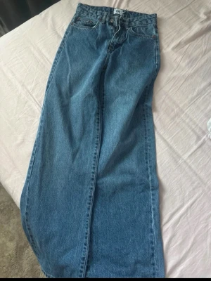 Blå jeans från 157 i modell XXS - Klassiska blå jeans från 157 i storlek XXS. Jeansen har raka ben, fem fickor och normalhög midja. Tillverkade i slitstarkt bomullsjeans-tyg med snygg blå tvätt och enkel design. Perfekta för dig som gillar en tidlös och clean look.