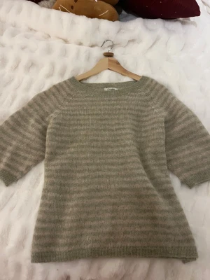 Randig stickad tröja från designbysi  - Mysig stickad tröja från designbysi i ljusbeige och gröna toner med randigt mönster. Den är typ alltid slutsåld och jättefin, har bara använt en gång. 