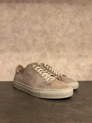 Axel Arigato Clean 90 sneakers - Snygga Axel Arigato sneakers i mocka med grå platt sula. Skorna har en rund tå och mjuk skinnpanel vid hälen för extra komfort. Perfekt för dig som gillar stilrena och neutrala färger. I bra skick, men tecken på normal användning finns:)