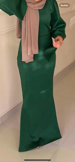 Grön långklänning med vida ärmar - Snygg grön långklänning med stilren, figurnära passform och vida, långa ärmar. Klänningen har rund halsringning och diskret dragkedja bak. Materialet är slätt och känns mjukt mot huden, perfekt för dig som gillar minimalistisk och elegant stil.