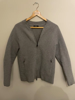 Grå fullzip från J.Lindeberg i storlek S - Säljer en stilren grå kofta från J.Lindeberg med diskreta ränder och hel dragkedja framtill. 😊Storlek S! Bara att skriva vid frågor 🙌