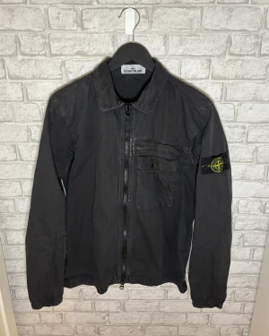 Stone Island jacka - Stone Island overshirt i klassisk svart färg med ikoniska patchen på armen. Tidlös och stilren modell som funkar perfekt till vardag. Använd men i överlag bra skick med normalt slitage som ger en snygg patina. Autentisk med certilogo. Hör av dig vid intresse 🙌