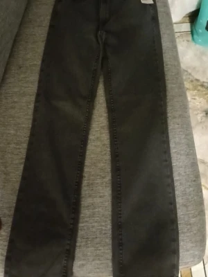 Svarta raka jeansbyxor - Svarta jeansbyxor med rak passform och klassisk design. Byxorna har fem fickor och synliga sömmar längs benen. Perfekta för dig som gillar en enkel och stilren look.