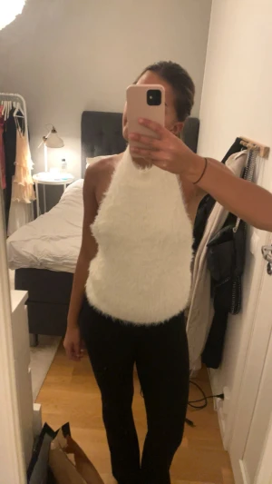 Vit fluffig halterneck topp från Zara - Superfin vit halterneck topp från Zara i storlek L men passar en M också, Toppen har en fluffig och mjuk pälsliknande yta som ger en unik och cool vibe. Modellen är ärmlös och har en hög hals som knyts i nacken.