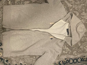 Polo Ralph Lauren  - En fin grå tröja med dragkedja, två fickor, huva och snören vid luvan.