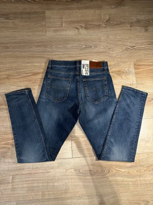 Tiger of Sweden  - Säljer ett par stilrena mörkblå jeans från Tiger of Sweden. Klassisk tvätt med lätt slitning framtill som ger en snygg och modern look.